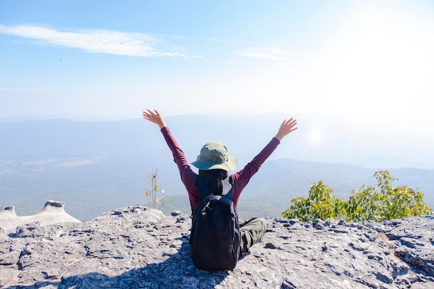 Ragazza turistica che si siede sulla pietra alla montagna che osserva vista panoramica