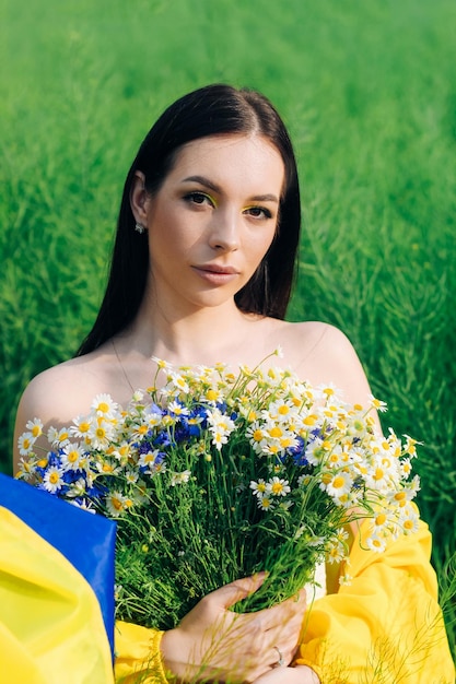 Ragazza ucraina con una bandiera blugialla in mano e un mazzo di fiori