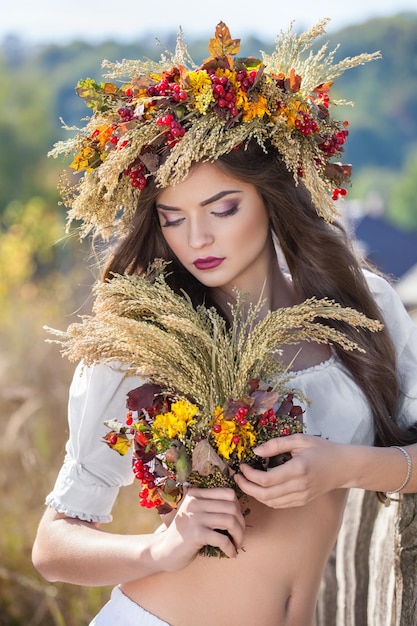 Ragazza ucraina con una corona colorata in testa e un bouquet di fiori selvatici in stile boho etnico