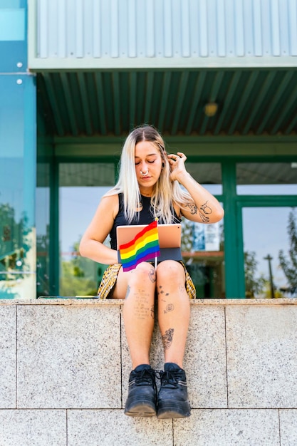Ragazza universitaria LGBT moderna tatuata che studia alla facoltà di filosofia con la bandiera dell'orgoglio