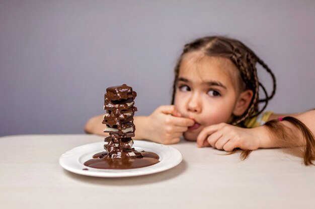 Ragazza versando cioccolata calda liquida su un mucchio di diversi pezzi di cioccolato