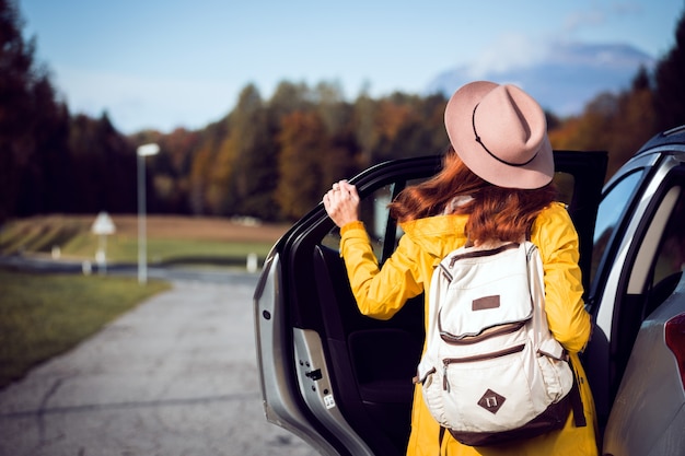 Ragazza vicino alla macchina e un bellissimo paesaggio di montagna sullo sfondo