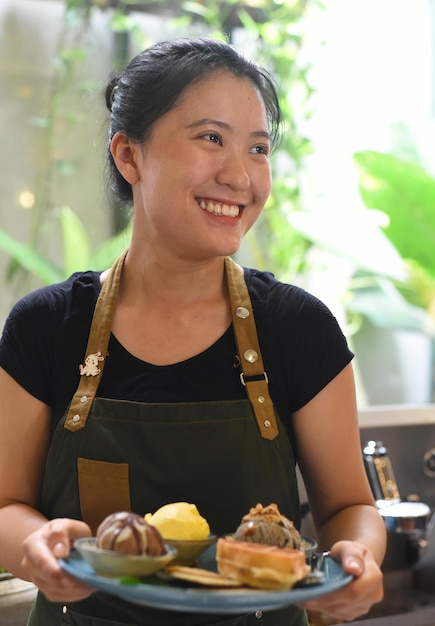 Ragazza vietnamita che serve gelato fatto in casa con waffle in una caffetteria.