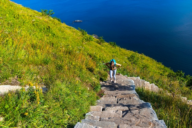 ragazza zaino in spalla che fa un'escursione su per le scale fino al famoso picco reinebringen nelle isole lofoten, norvegia