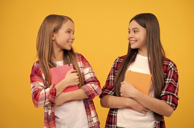 Ragazze adolescenti felici in camicia a scacchi casual con la sorellanza dei taccuini