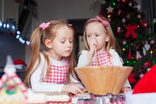 Ragazze adorabili che cuociono i biscotti del pan di zenzero per la cucina di Natale a casa