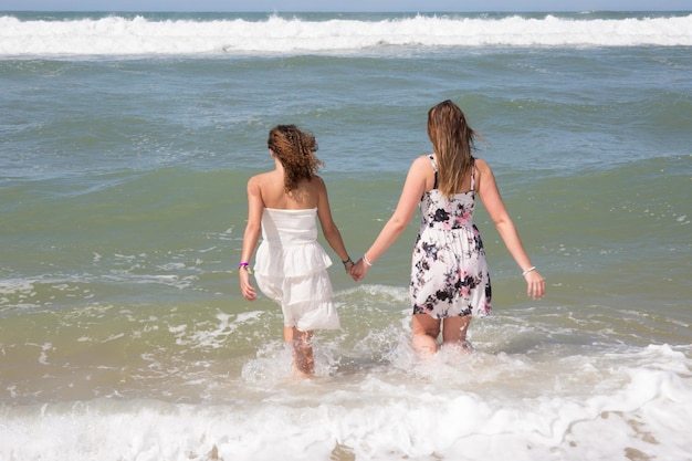 Ragazze al mare Due giovani donne entrano in mare vista posteriore