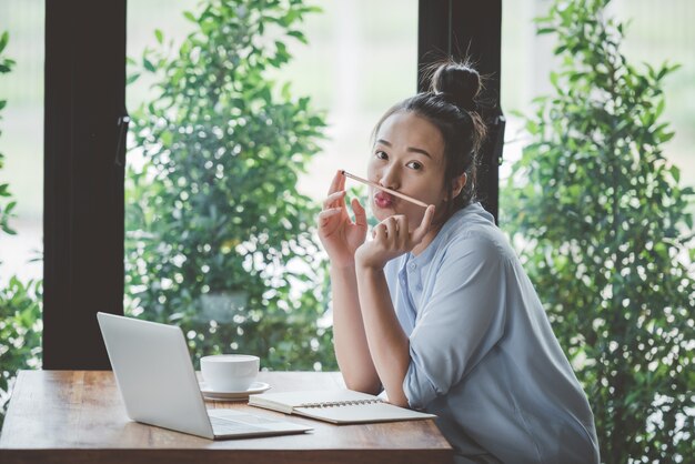 Ragazze asiatiche che si siedono lavorando confortevolmente a casa.