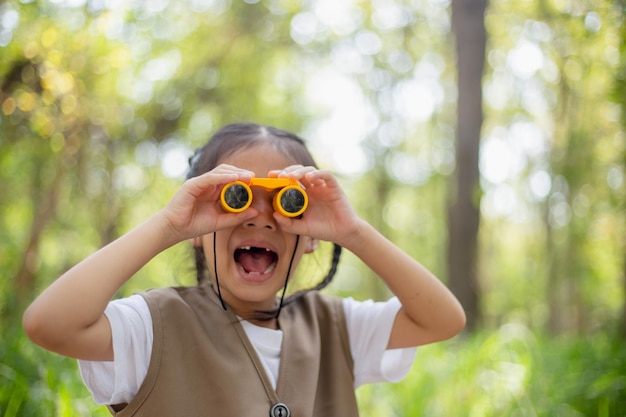 Ragazze asiatiche felici che guardano avanti e bambini sorridenti con il binocolo nel parco Concetto di viaggio e avventura Vacanza in libertà