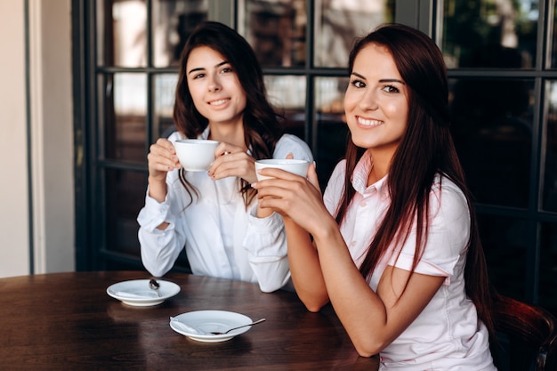 Ragazze attraenti in posa nella caffetteria, bere caffè dolce. Flusso di lavoro