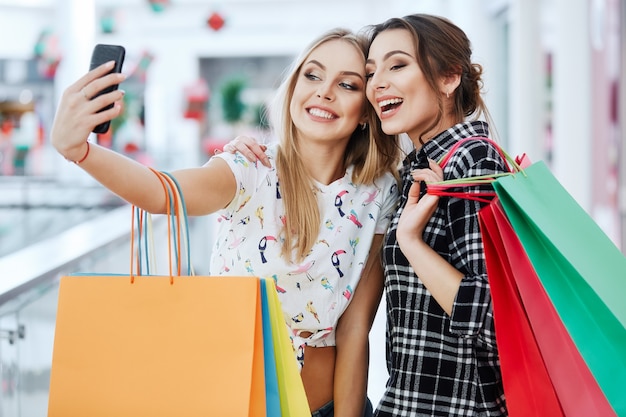 Ragazze attraenti nel centro commerciale con i sacchetti