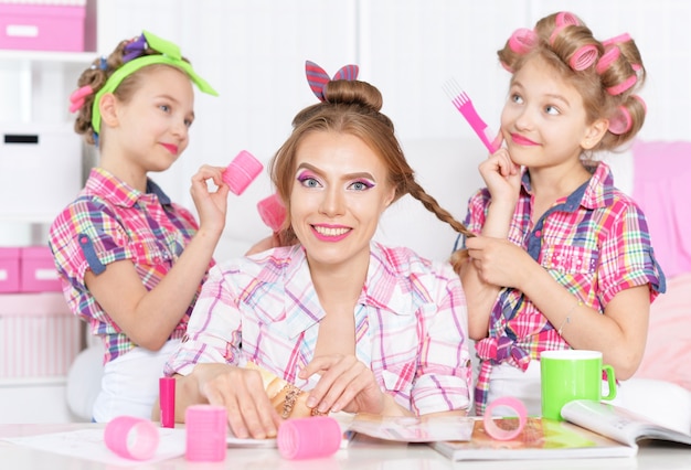 Ragazze carine tweenie con la madre in bigodini che fa l'acconciatura per la loro madre