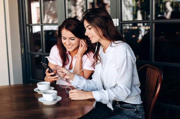 Ragazze che ascoltano la musica che si siedono in caffè