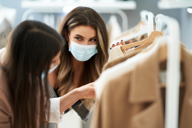 Ragazze che fanno shopping in negozio con vestiti che indossano maschere. Foto di alta qualità