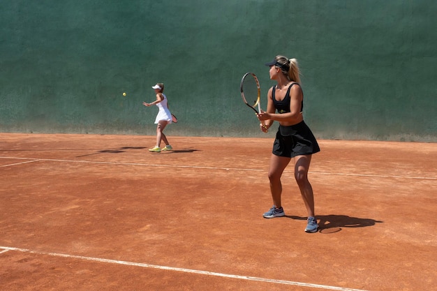 Ragazze che giocano una partita di doppio di tennis su un campo in terra battuta