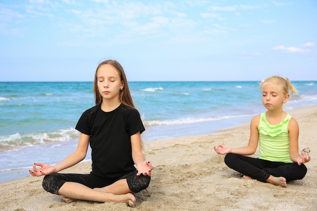 Ragazze che praticano yoga sulla spiaggia