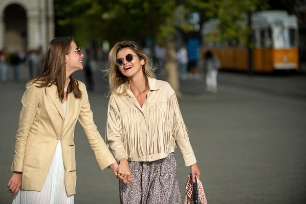 Ragazze che ridono con emozioni positive che esprimono che camminano per la strada della città viaggiando in europa