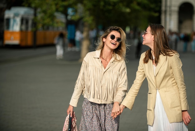 Ragazze che ridono con emozioni positive che esprimono che camminano per la strada della città viaggiando in europa