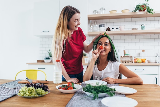 Ragazze che scherzano in cucina giocando con le verdure