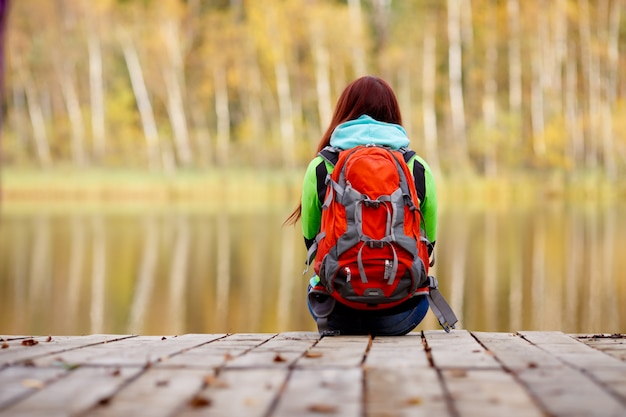 Ragazze che si siedono indietro sul ponte nella foresta di autunno