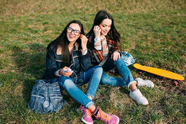 Ragazze che si siedono sul prato ascoltando musica