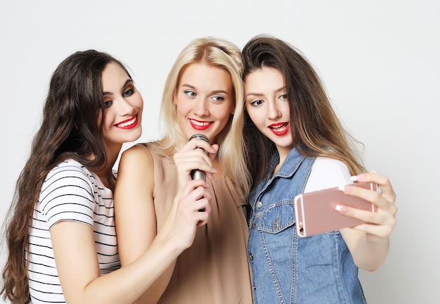 Ragazze di bellezza con un microfono che cantano e si divertono insieme