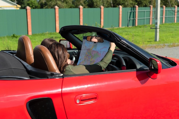 Ragazze felici che guidano un'auto cabriolet rossa durante il viaggio divertendosi insieme