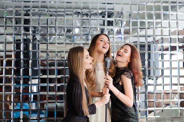 Ragazze felici divertirsi cantando ad una festa.