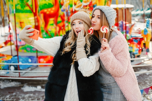 ragazze giovani e alla moda in abiti invernali stanno camminando nella città solare con dolciumi