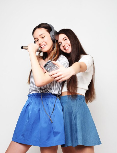 Ragazze hipster di bellezza con un microfono che cantano e scattano foto