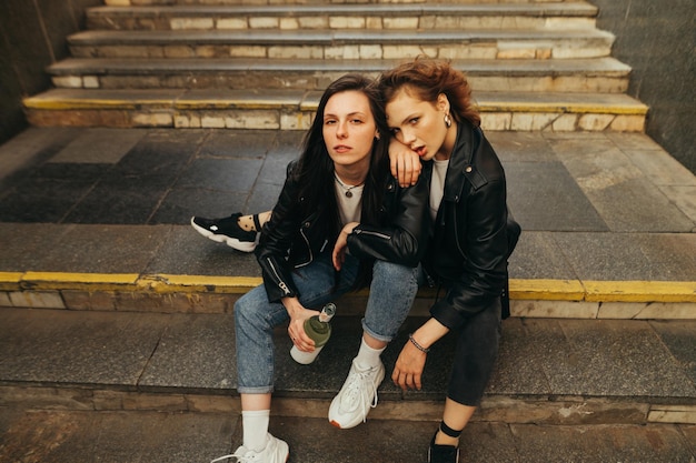 Ragazze in giacche di pelle sedute nel sottosuolo sulle scale