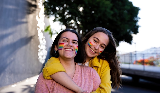 ragazze lesbiche che si divertono a dipingersi e con la bandiera lgtb il giorno dell'orgoglio lgtb concept