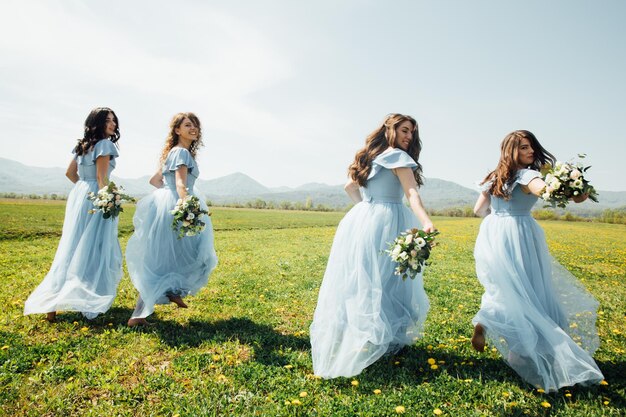 ragazze molto belle, damigelle d'onore che corrono divertite in abiti blu e fiori