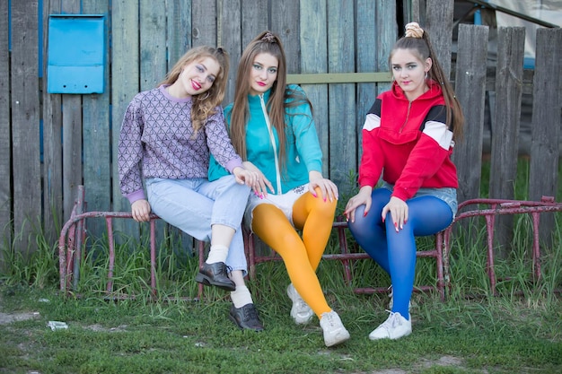 Ragazze nello stile degli anni Novanta. Tre ragazze di campagna sono sedute su una panca di legno.