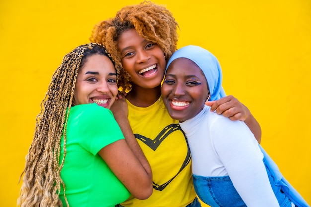 Ragazze sorridenti multietniche che posano insieme su uno sfondo giallo