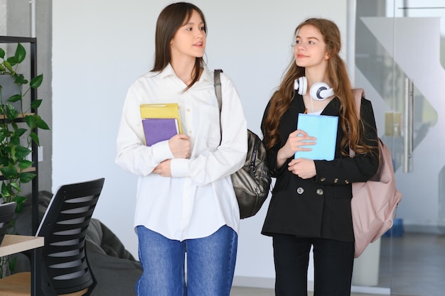 Ragazze sorridenti nel corridoio del liceo Due studenti universitari di sesso femminile che parlano dopo la lezione