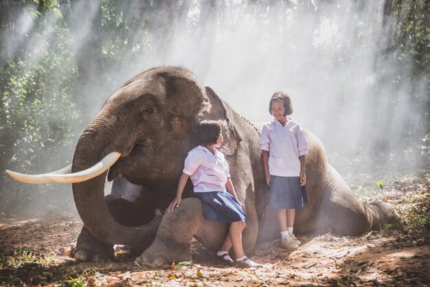 Ragazze tailandesi che giocano dopo la scuola nella giungla vicino al loro amico elefante