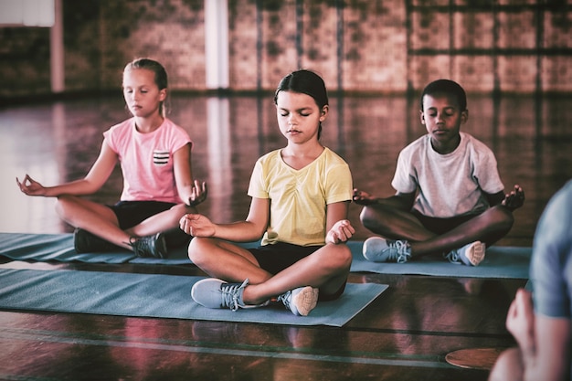 Ragazzi delle scuole che meditano durante la lezione di yoga