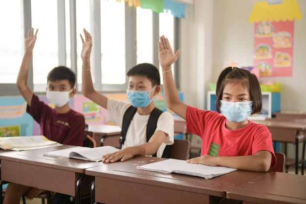 Ragazzi delle scuole con maschera di protezione contro il virus dell'influenza a lezione in aula