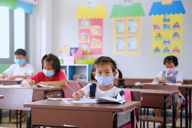 Ragazzi delle scuole con maschera protettiva contro il virus dell'influenza a lezione in classe