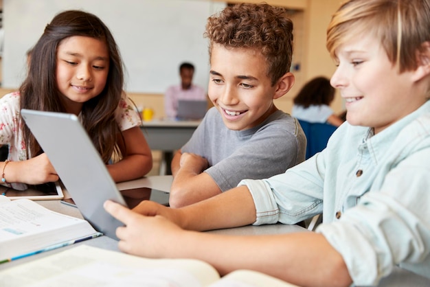 Ragazzi delle scuole elementari che utilizzano computer tablet in classe scolastica