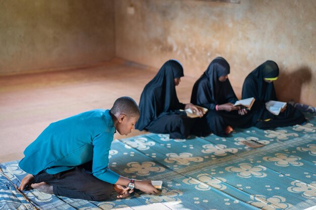 Ragazzi e ragazze adolescenti africani seduti e leggendo un libro in una scuola povera, foto di alta qualità