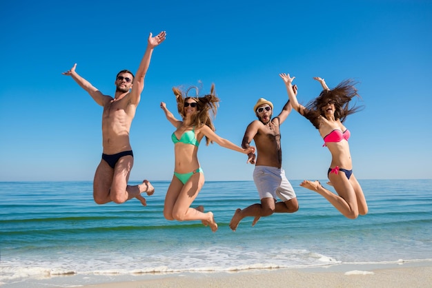 Ragazzi e ragazze che saltano sulla spiaggia.