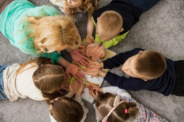 Ragazzi e ragazze in cerchio. Bambini felici che si divertono. i bambini si sdraiano insieme. Bambini felici sdraiati sul pavimento in cerchio con le mani. Vista dall'alto. Gruppo di bambini bel sorriso sdraiato sul pavimento