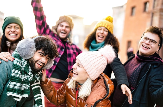 Ragazzi e ragazze internazionali che si fanno selfie con la faccia buffa indossando abiti caldi alla moda