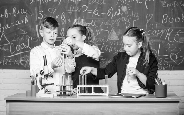 Ragazzi e ragazze si divertono con l'esperimento chimico La chimica organica è lo studio di composti contenenti carbonio Chimica affascinante Reazioni chimiche di base Gli alunni delle scuole di gruppo studiano chimica a scuola