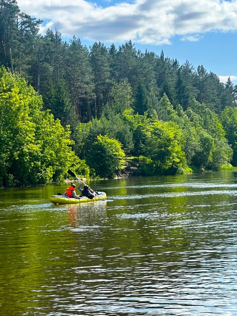 Ragazzi, giovani donne e uomini navigano sul fiume in estate.