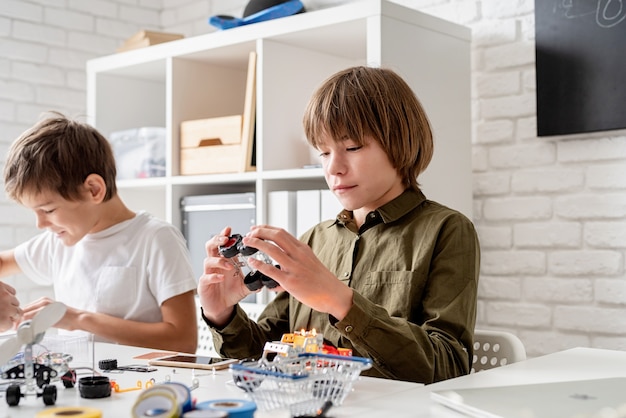 Ragazzi giovani e divertirsi costruendo insieme auto robot in officina