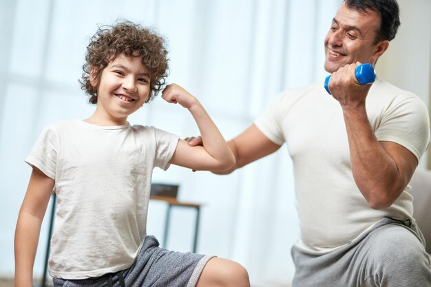 Ragazzi in forma piccolo bambino ispanico che sorride alla telecamera mostrando i suoi bicipiti mentre si allena