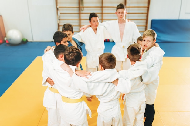 Ragazzi in kimono su kid judo training indoor. Giovani combattenti in palestra, arti marziali per la difesa